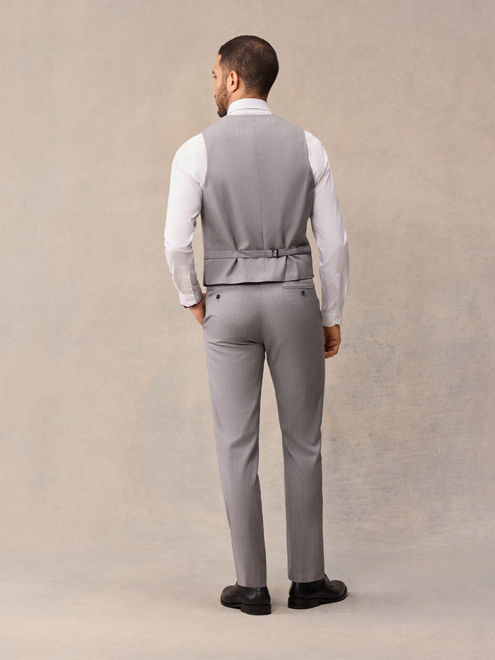 Back view of man in light grey suit vest, full-length, black shoes