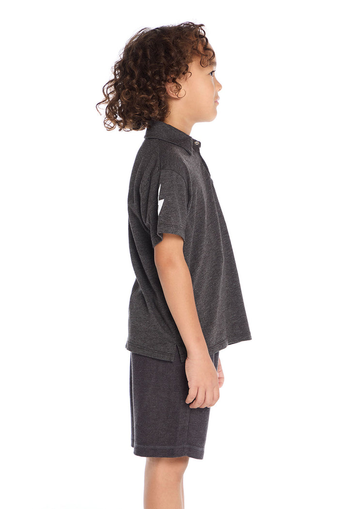 Side view of boy wearing the Chaser Kids dark gray Lightning Bolt Classic Tee showing the short sleeves and lightning bolt detail on the sleeve, paired with matching shorts on a white background