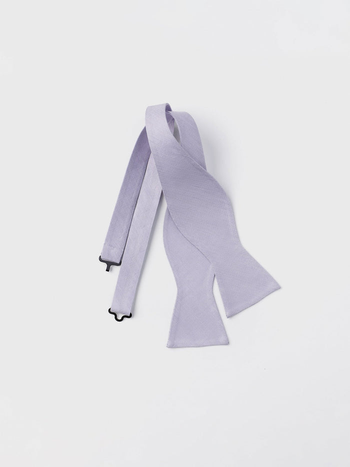 Lilac linen-silk bow tie, untied and draped, flat lay on white background