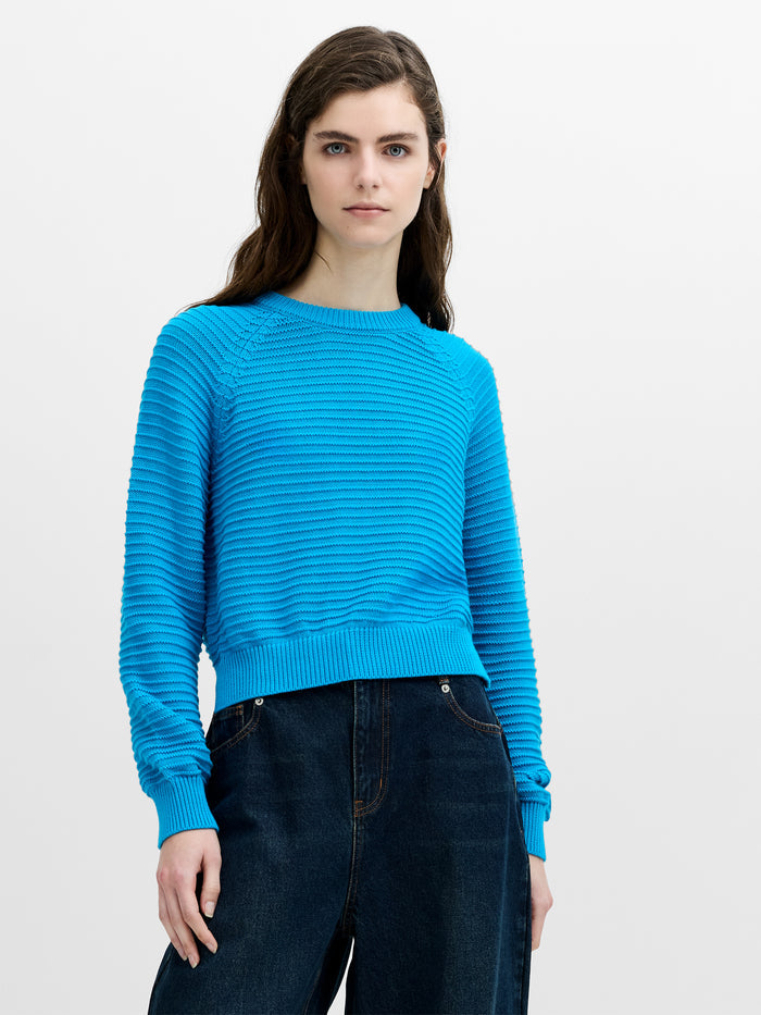 Woman wearing a purl knit regular fit jumper with a crew neck and long raglan sleeves.