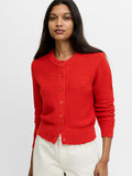 A woman wearing a red knit cardigan with a classic crew neck, button down fastening and long sleeves.