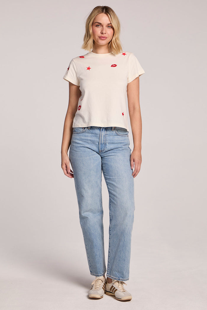 Full body front view of a woman wearing the Chaser Lips Embroidery Tee and sneakers on a neutral background
