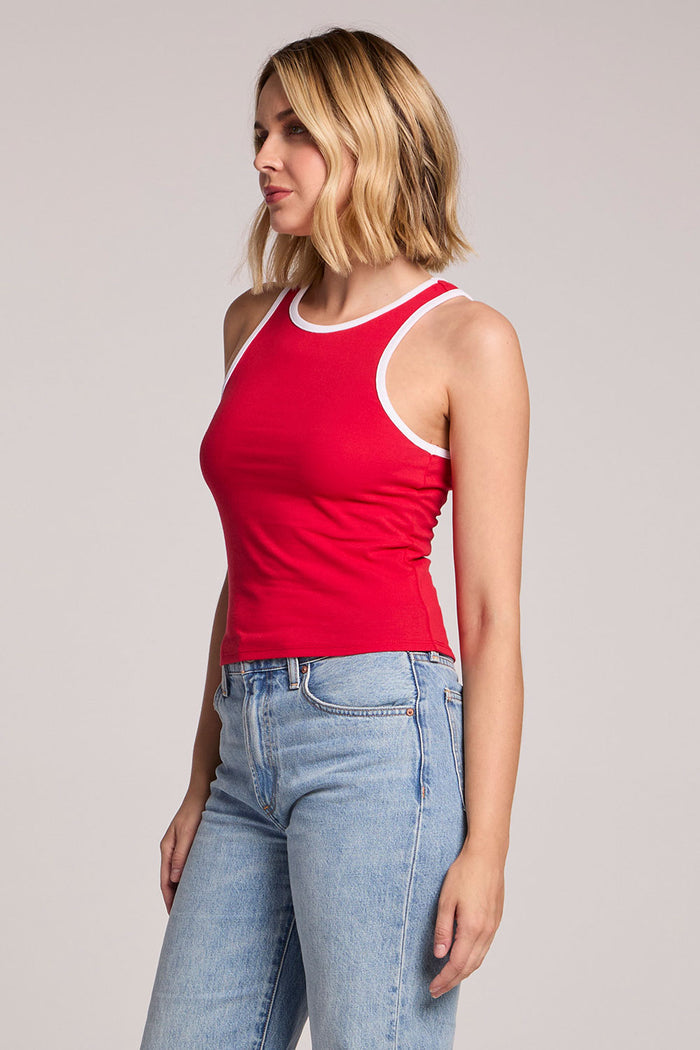 A side view of a woman wearing the Chaser Lisbon Cardinal Red Tank and jeans on a neutral background