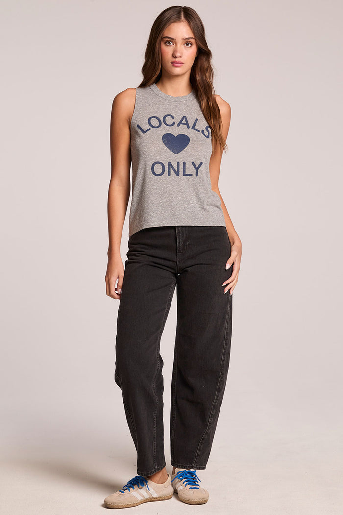 Front view of a woman wearing the Chaser  Locals Only Tee and sneakers on a neutral background