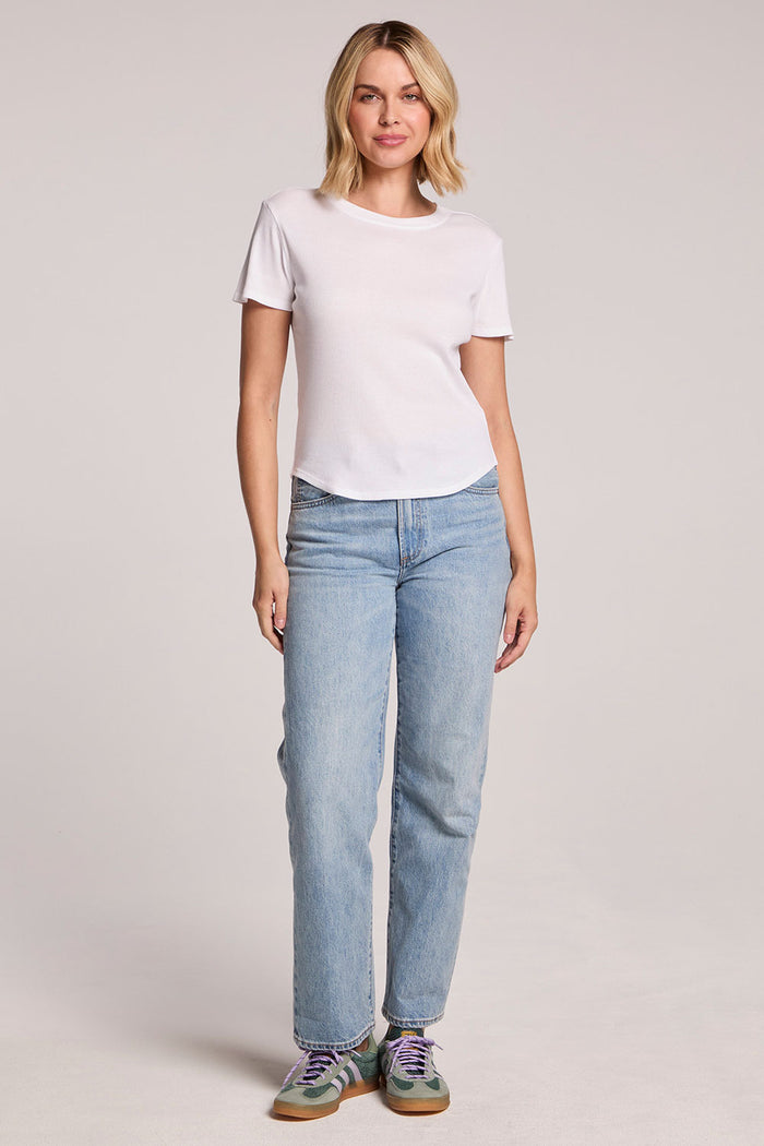Front full body view of a woman wearing the Chaser Louisa White Tee and sneakers on a neutral background