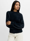 A woman wearing a dark grey fluffy jumper with a crew neck, long sleeves and a relaxed fit.