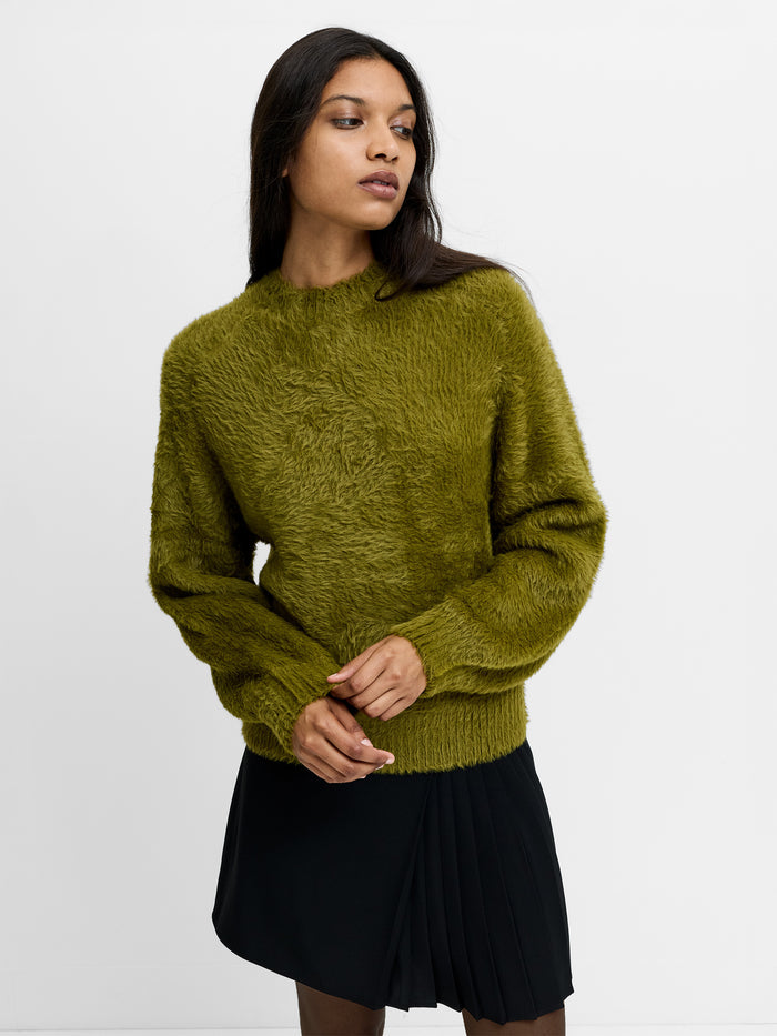 A woman wearing a green fluffy knit jumper with a crew neck, long sleeves and a relaxed fit.
