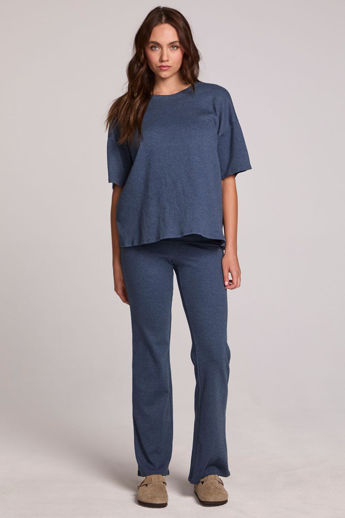 Full body front view of a woman wearing the Chaser Lunnah Dark Denim Top and blue pants on a neutral background