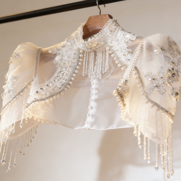 Luxury bridal capelet with high neckline, hand embroidered tulle, pearls, crystals and sparkling crystal fringe.
