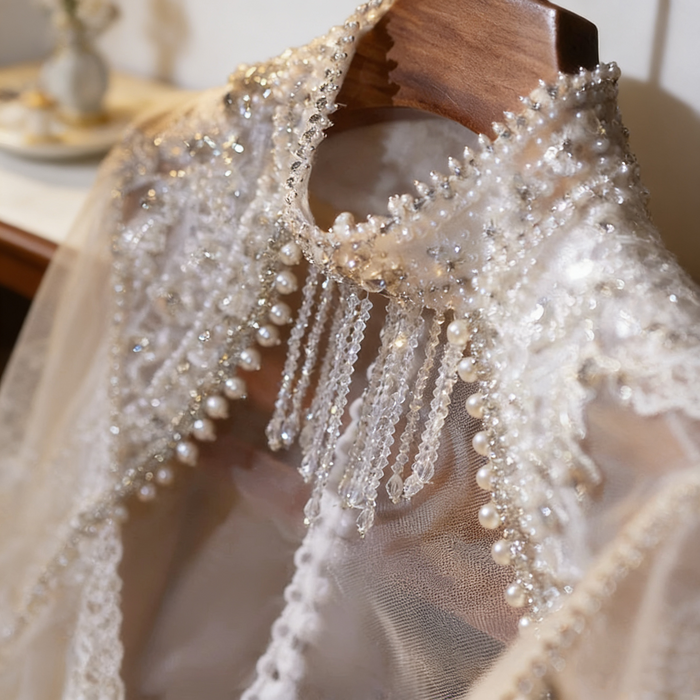 Luxury bridal capelet with high neckline, hand embroidered tulle, pearls, crystals and sparkling crystal fringe.