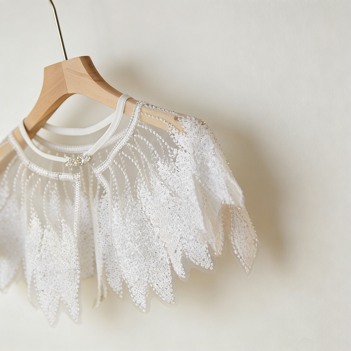 Luxury Swan Lake inspired ivory bridal capelet with illusion tulle and hand-embroidered sequin feather motifs.