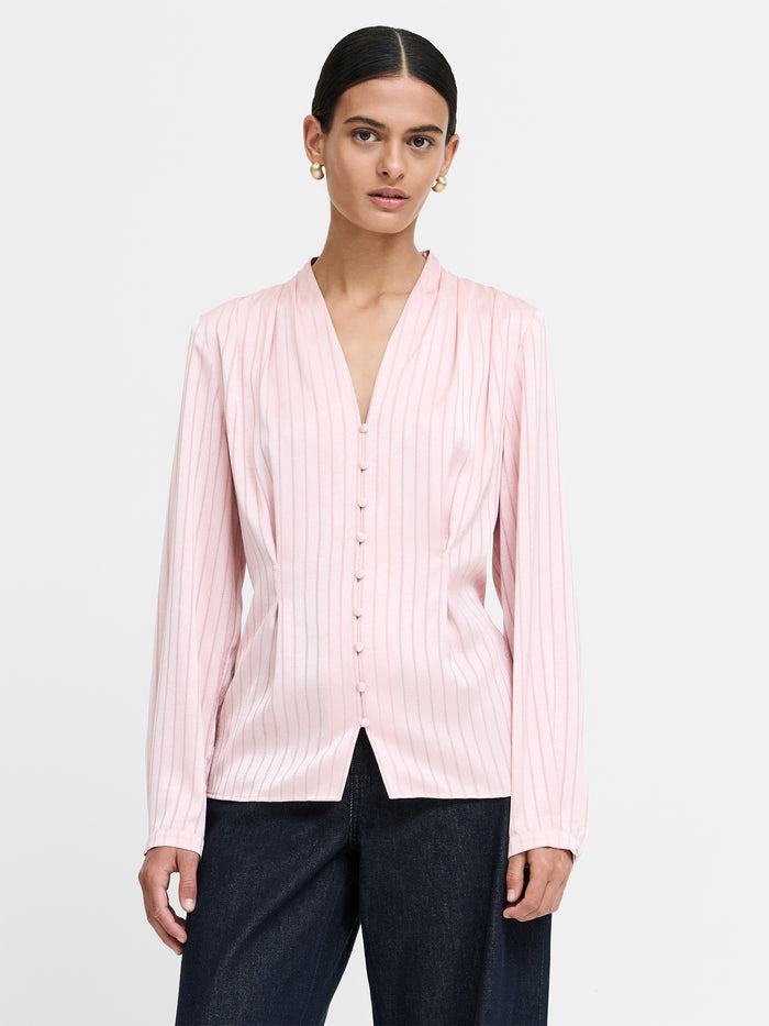 A woman wearing a satin striped pin blouse with a V-neckline, long sleeves, a button through fastening and a regular silhouette.