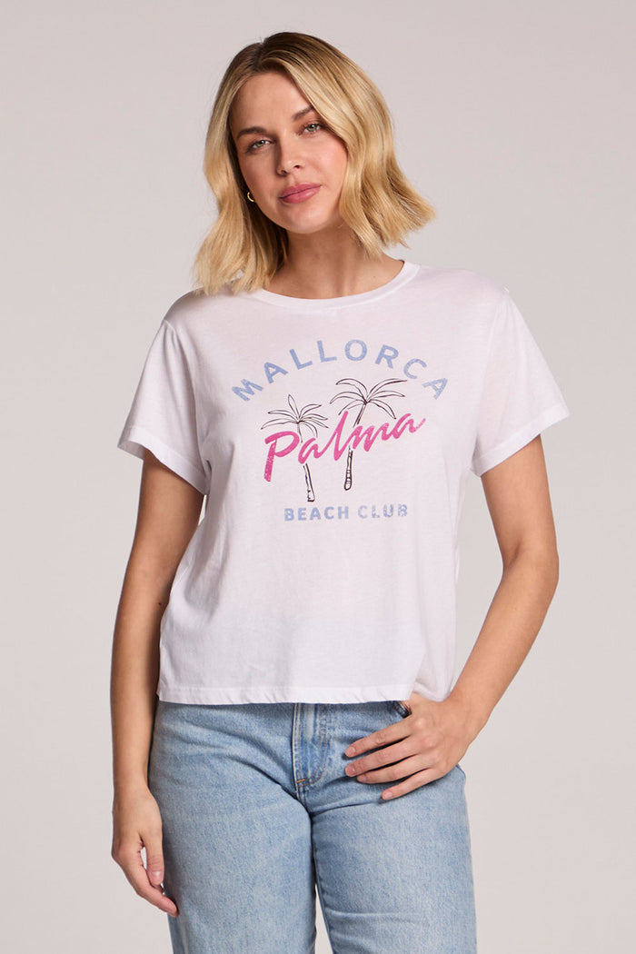 Front view of a woman wearing the Chaser  Mallorca Beach Club Tee and jeans on a neutral background