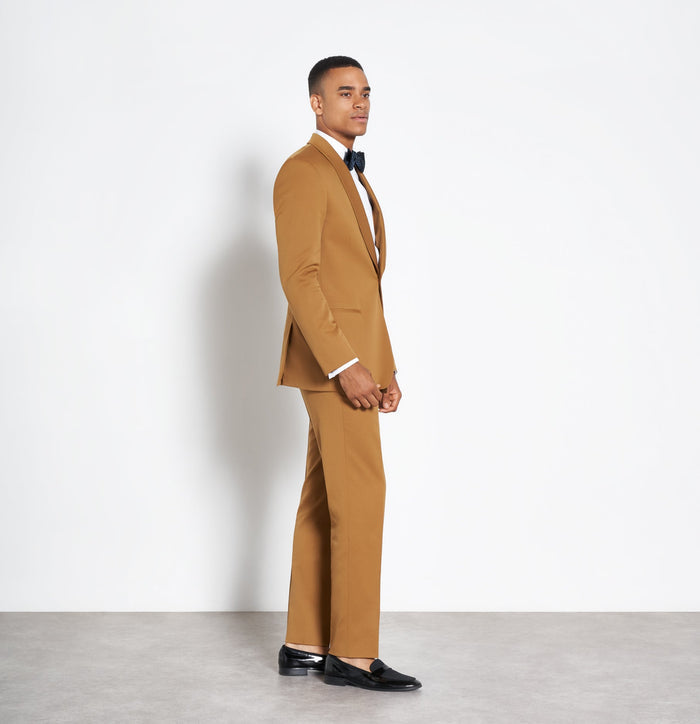 Side profile of man in marigold shawl-lapel tuxedo suit and navy bow tie
