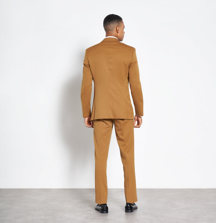 Back view of man in marigold shawl-lapel tuxedo, full length, white background
