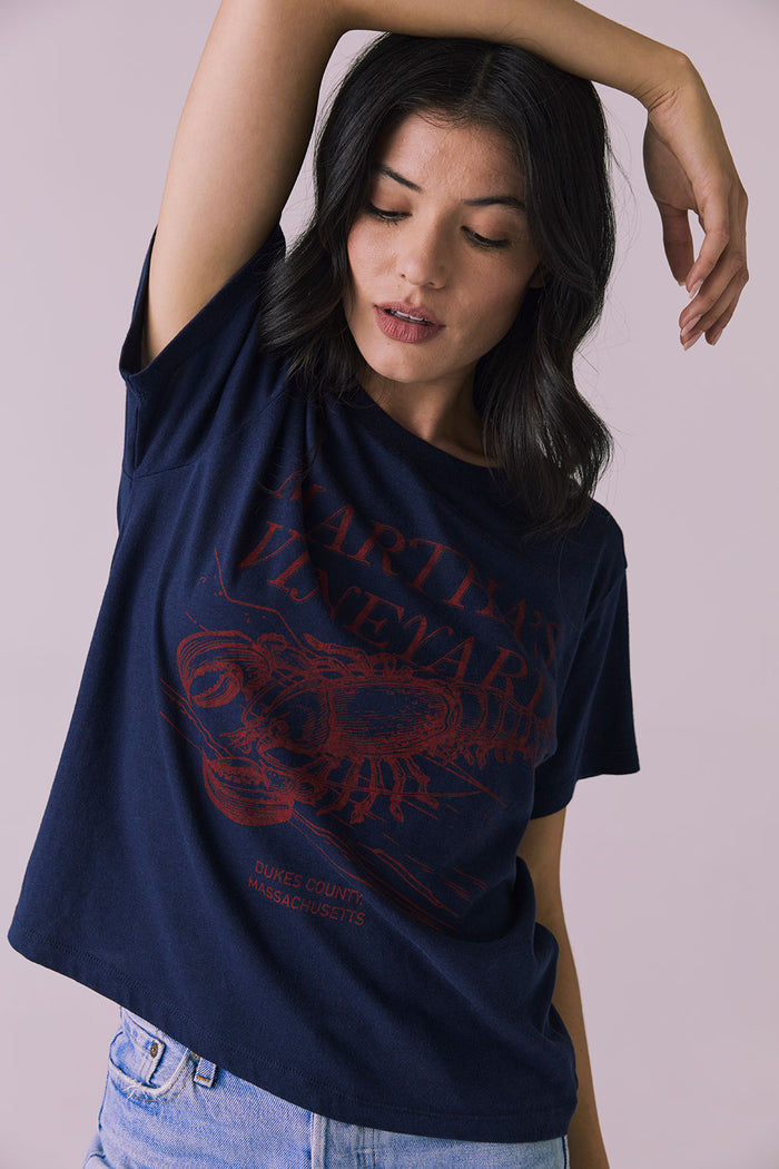 Close-up arms-up view of Chaser Brand Martha’s Vineyard Tee in Navy showing distressed red lobster print and easy neckline