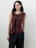 A woman wearing a soft burgundy sleeveless Top with a draped neckline, a metal ring detail and a fitted silhouette.