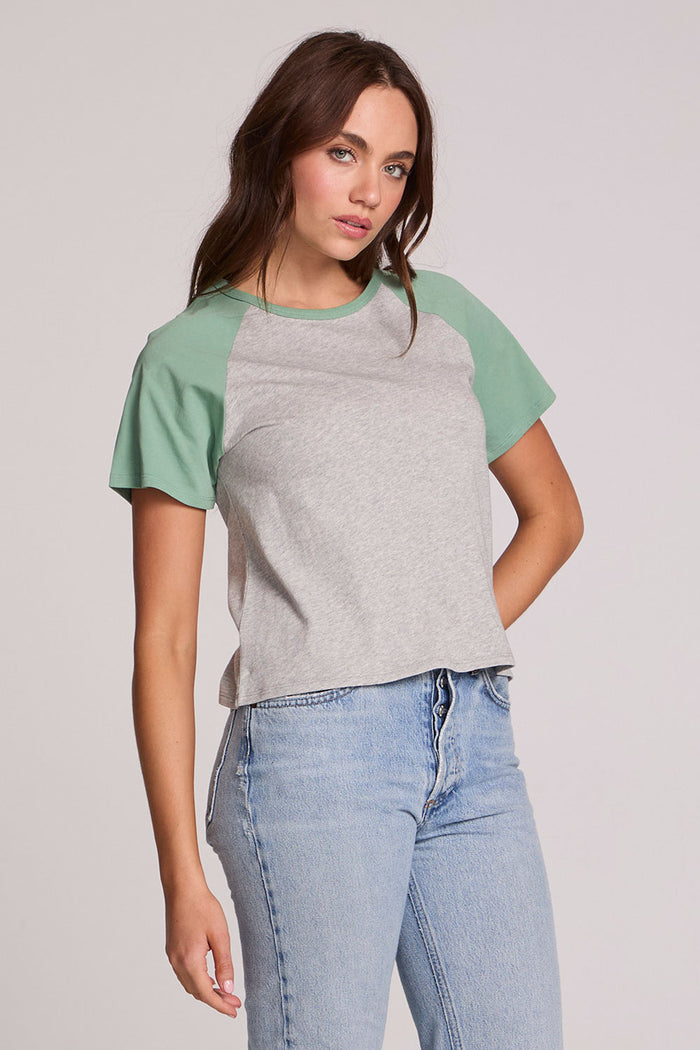 Front view of a woman wearing the Chaser Maybel Verdelle and Heather Grey Raglan Tee and bluejeans on a neutral background