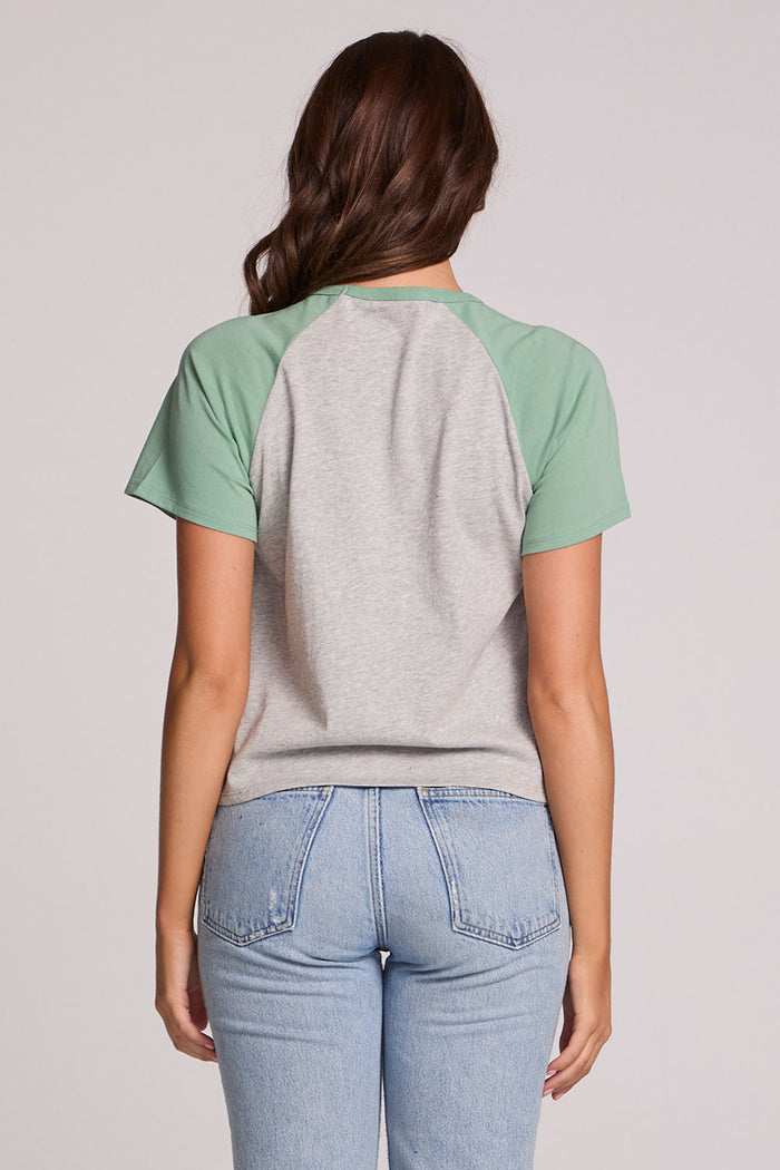 Back view of a woman wearing the Chaser Maybel Verdelle and Heather Grey Raglan Tee and jeans on a neutral background