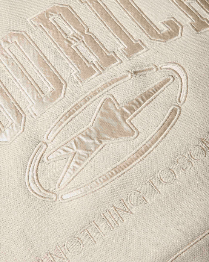 Close-up of a beige embroidered fabric with the Hoodrich branding