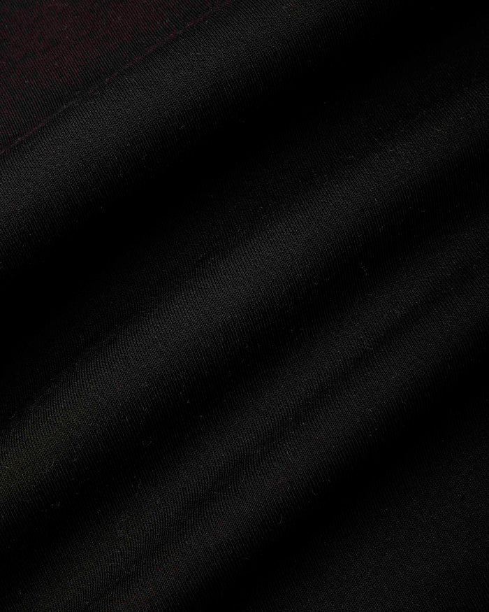 A close-up of a black fabric texture with soft diagonal folds and a subtle sheen.