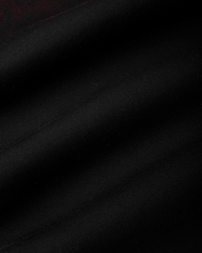 A close-up of black fabric with soft diagonal folds and a subtle woven texture.