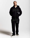Person wearing a black 'HOODRICH' branded tracksuit on a white background