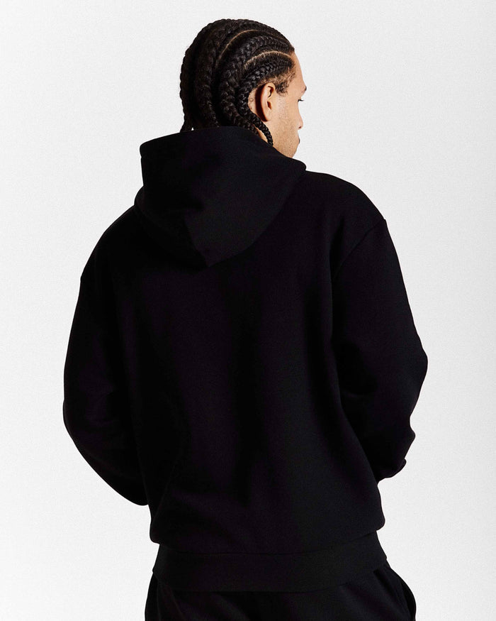 Person wearing a black hoodie from behind on a white background