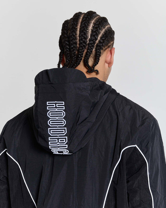Person wearing a black jacket with 'HOODRICH' branding on the back against a light gray background
