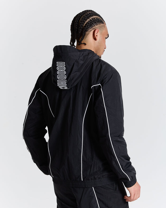 Person wearing a black tracksuit with white accents on a plain background