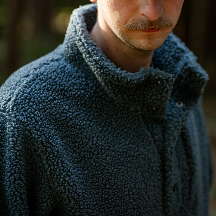 Man in Pladra Men's Cypress Sherpa Fleece—Atlantic Blue, outdoors, face partly visible, mustache showing.