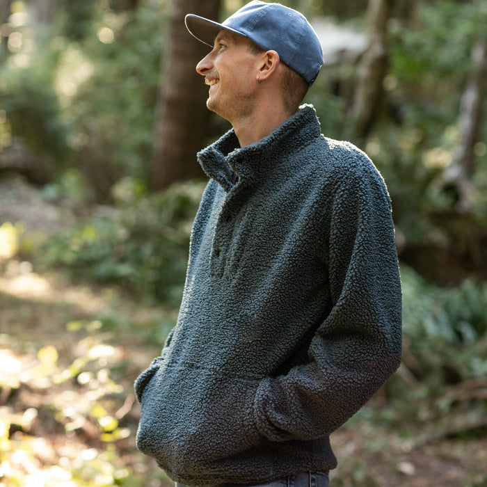 Man in an Atlantic Blue Pladra Men's Cypress Sherpa Fleece stands smiling outdoors, looking to the side.