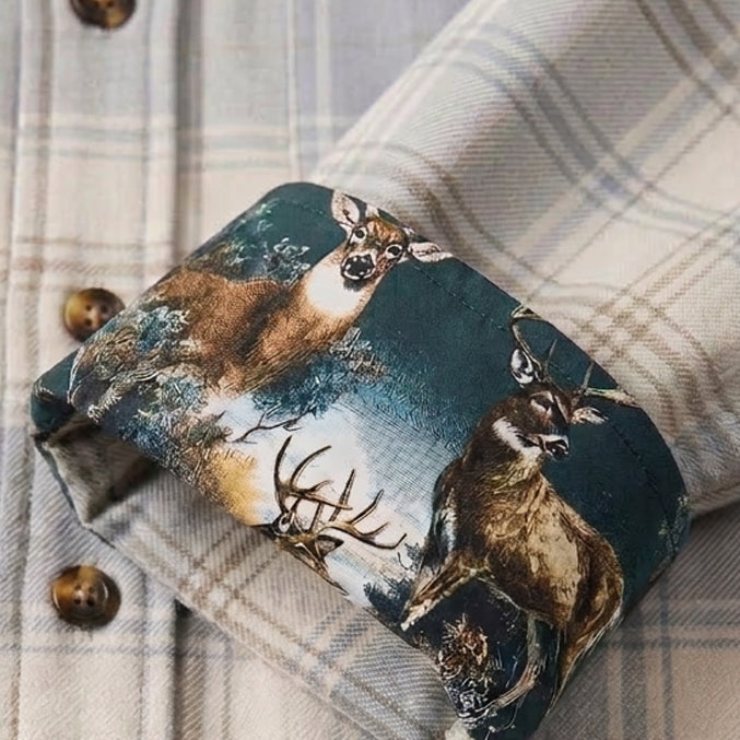 A close-up of the Men's Every Day Flannel Shirt - Windigo White Heather with its cuff turned up, showing an inner lining printed with deer and wilderness scenes—ideal for outdoor wear.