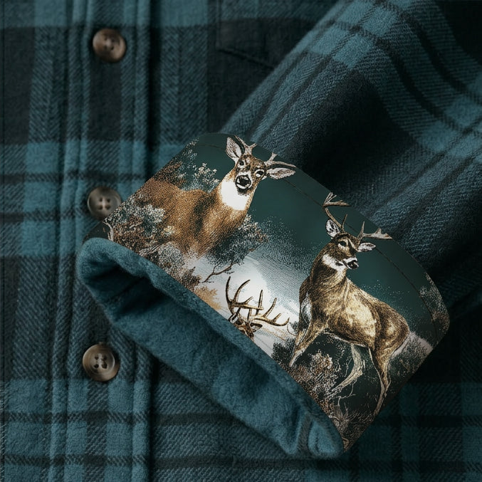 A close-up of the Men's Fireside Flannel - Fjord Green shows the cuff turned up to reveal a printed lining with two deer amid a forest, highlighting the shirt’s teal and black plaid pattern.
