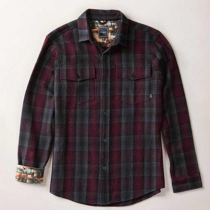 The Men's Fireside Flannel - Hickory Red is a long-sleeve button-up made from organic cotton flannel in maroon and dark gray plaid, with chest pockets and nature scene lining at the cuffs and collar for added style.