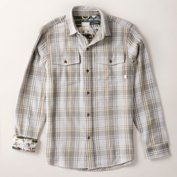 The Men's Fireside Flannel - Quartz Grey is a long-sleeve button-up shirt made from soft organic cotton flannel in gray, white, and tan plaid, featuring two chest pockets with button flaps and colorful printed lining inside the cuffs and collar.
