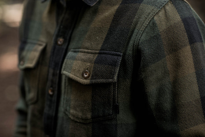 Close-up of a person wearing the Pladra Men's Fireside Flannel in Woodland Green with flap pockets.