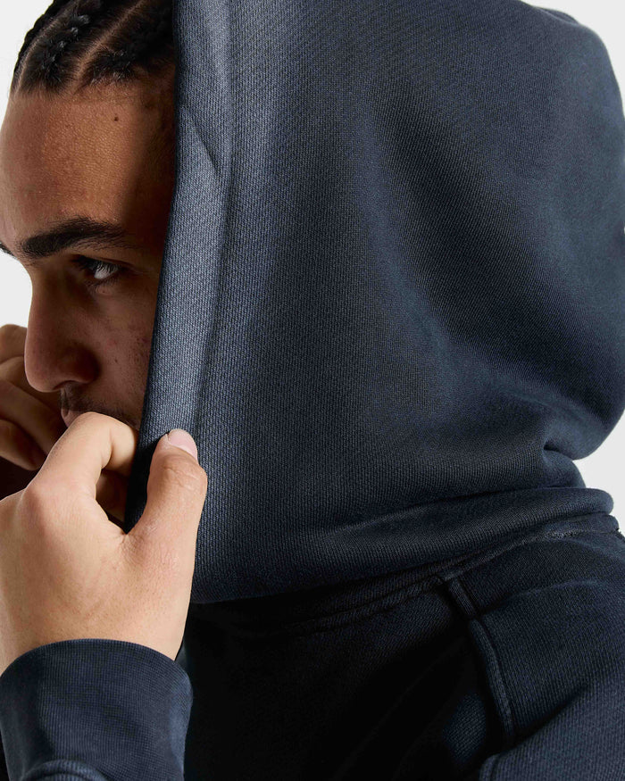 Person wearing a dark blue hoodie with their face partially covered.