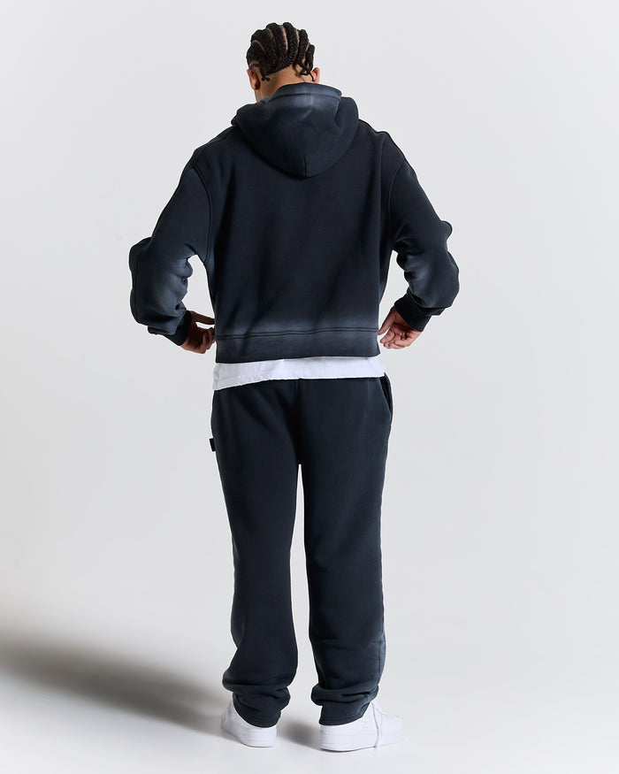 Person wearing a black tracksuit with a hood on a white background
