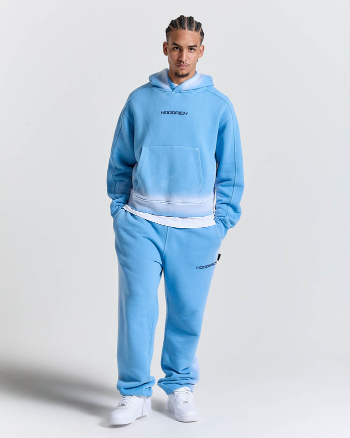 Person wearing a blue tracksuit with 'Hoodrich' branding on a light gray background