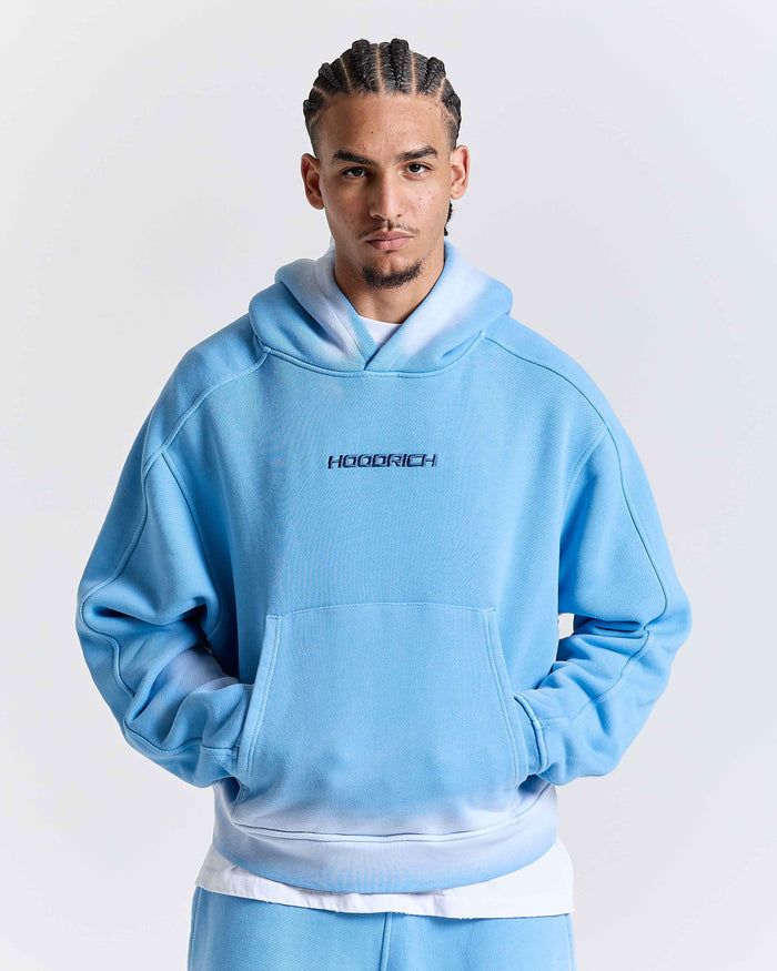 Person wearing a light blue hoodie with 'HOODRICH' branding on a white background