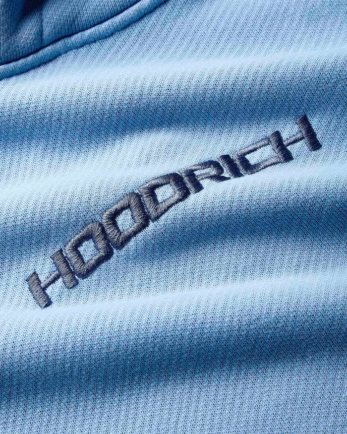 Close-up of a blue fabric with 'Hoodrich' embroidered on it