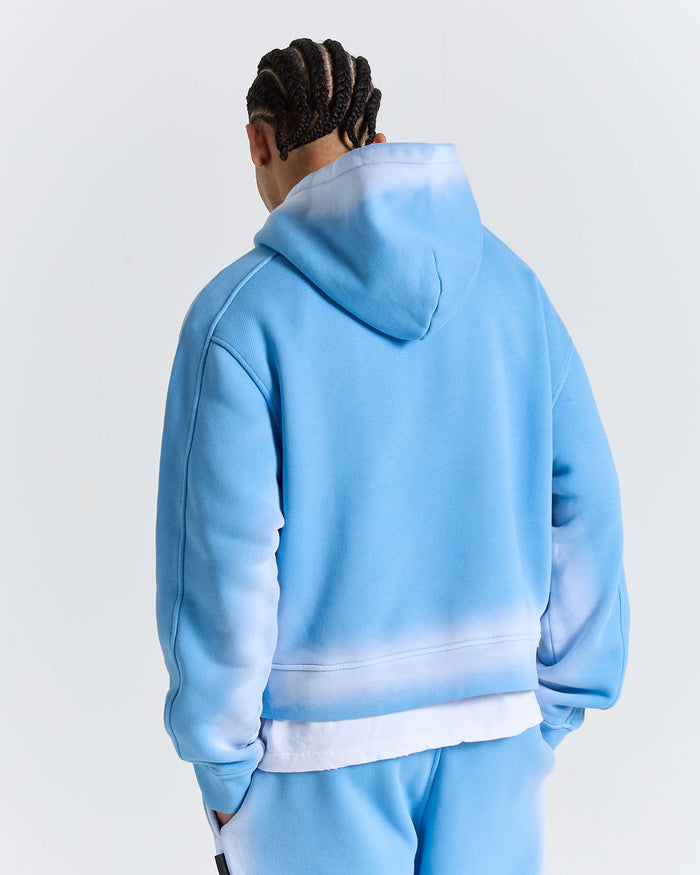 Person wearing a light blue hoodie and pants on a white background