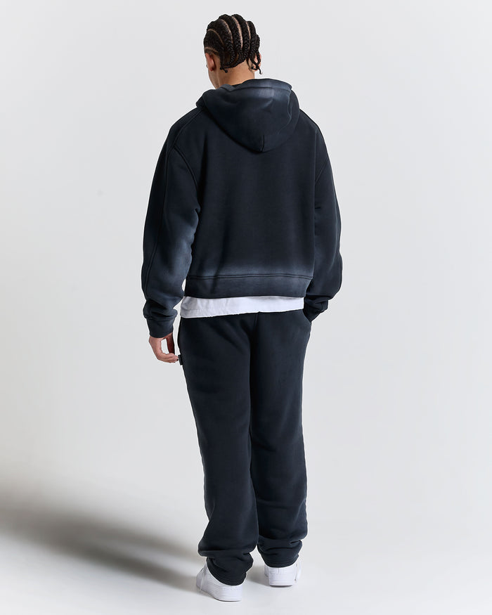 Person wearing a black hoodie and pants on a white background
