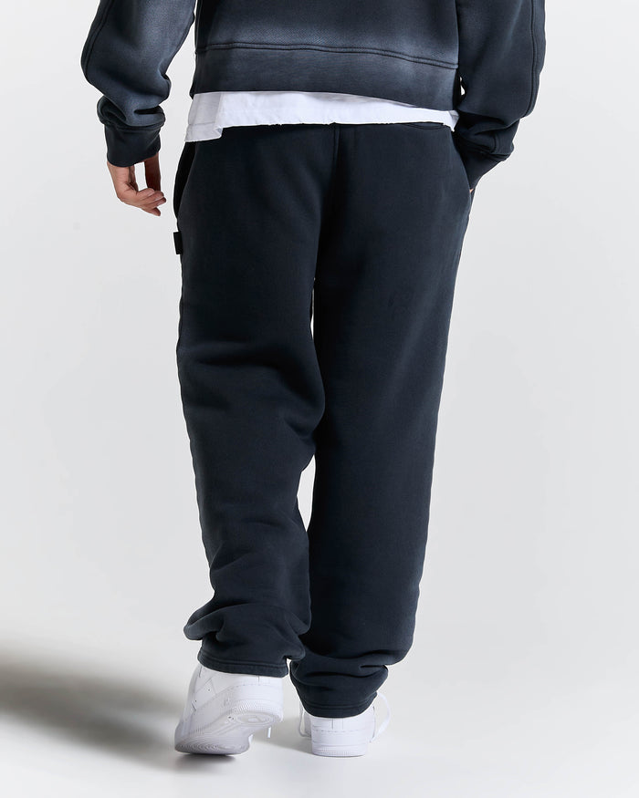 Person wearing dark blue sweatpants and white shoes on a light gray background