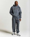 Person wearing a gray 'Hoodrich' hoodie and pants on a white background