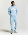 Person wearing a light blue tracksuit with 'HOODRICH' text on a plain background
