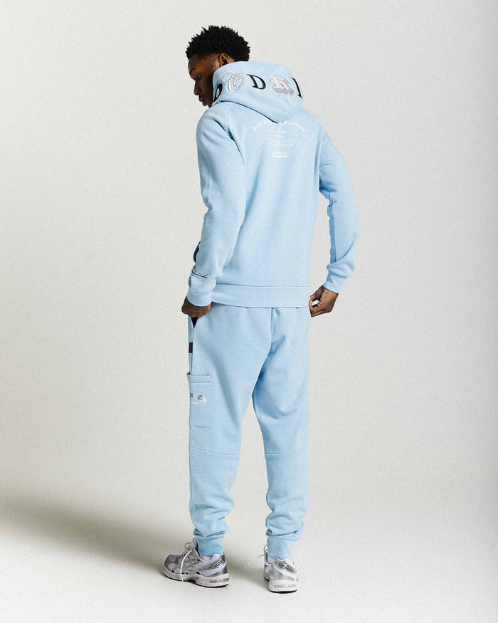 Person wearing a light blue tracksuit with brand logo on a white background