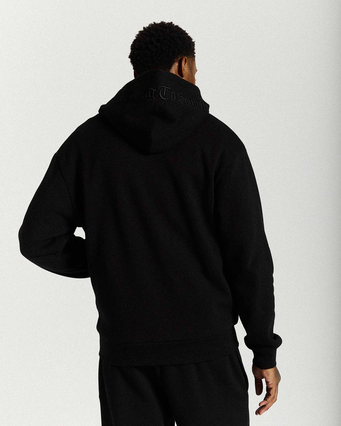 Displays a model wearing the Black 'Hoodrich' branded men's Inkline Full Tracksuit