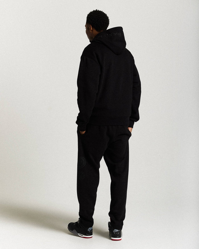 Displays a model wearing the Black 'Hoodrich' branded men's Inkline Full Tracksuit